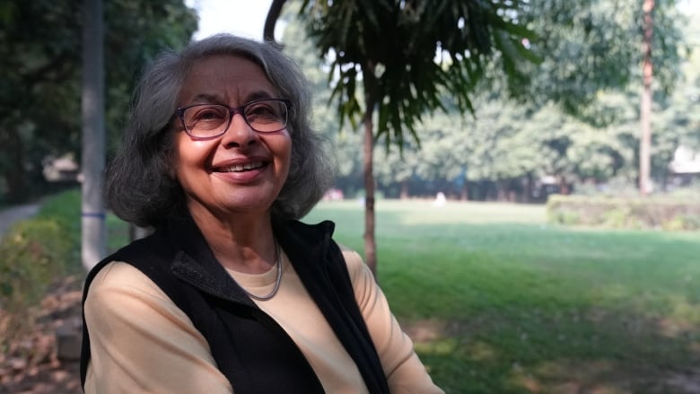 A woman wearing glasses sitting outdoors.