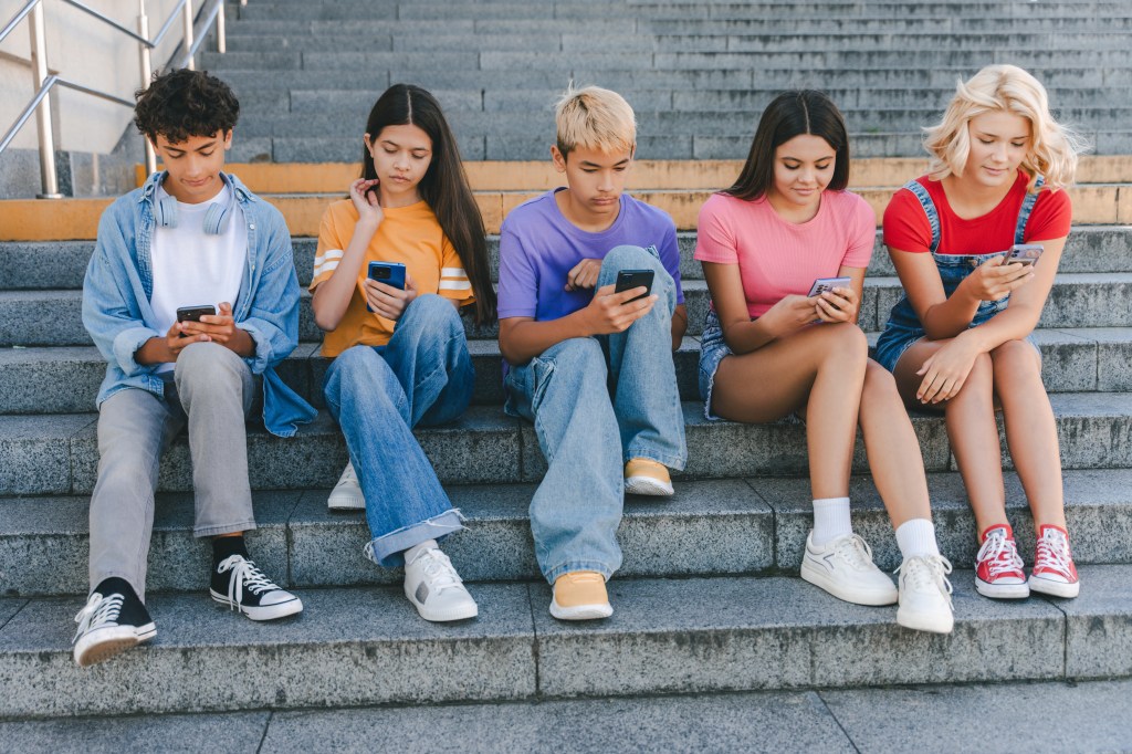 Stock photo of teens looking at smartphones