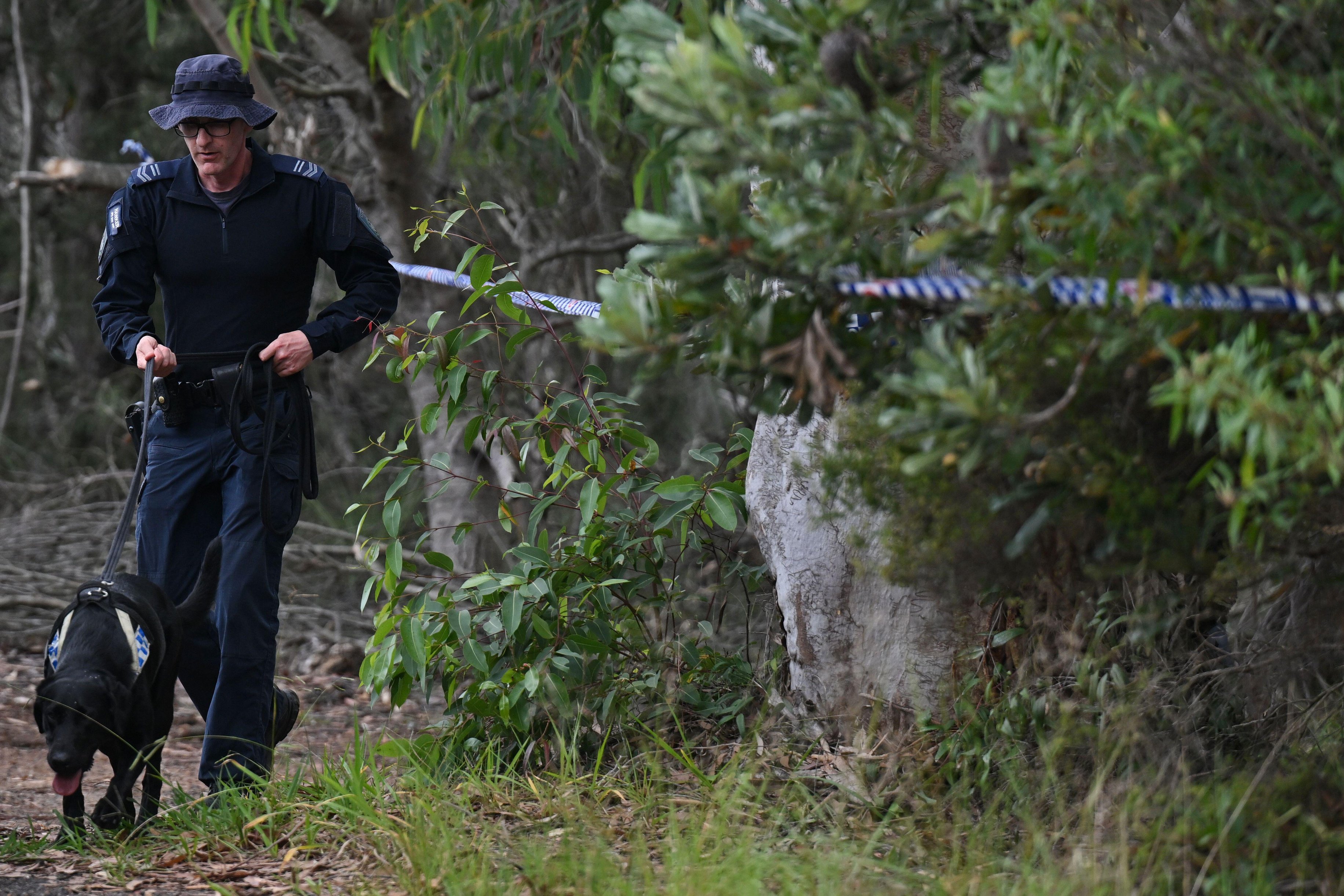 Police search the remote property where two bodies were found 'stuffed in surf bags'