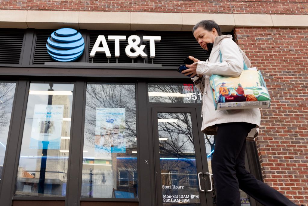 A pedestrian looking at a cell phone outside an AT&T retail store during an investigation into outages in Washington, USA - 22 Feb 2024.