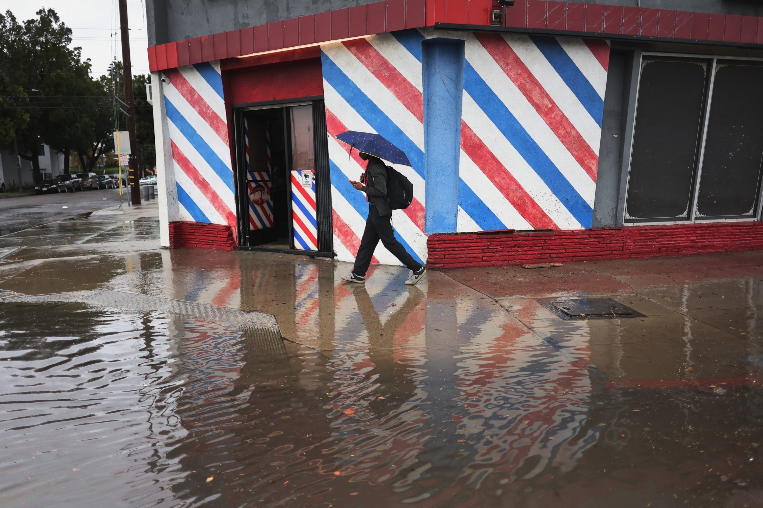 PHOTO:  A man walks by a flooded road during a rain storm in Long Beach, Calif., on Feb. 1, 2024.