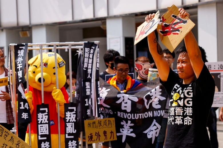 On the right, an exiled Hong Kong activist tears apart a cardboard with the words Article 23 on it, in Taipei, Taiwan.