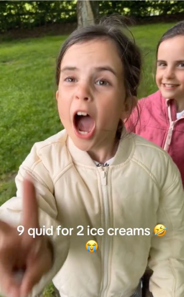 Eight-year-old twin girls from Burnley reacting to today's ice cream prices, one girl with her mouth open and her finger up in a TikTok video.
