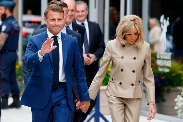 French President Emmanuel Macron, left, and his wife Brigitte leave the polling station after voting in the first round of parliamentary elections in Le Touquet, northern France 